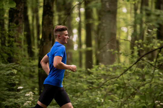 young boy running cross country in summer forest