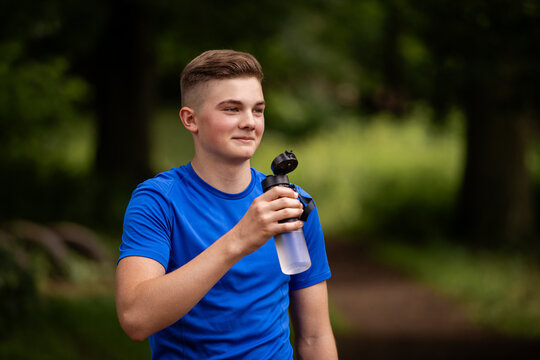 young caucasian man in a blue shirt holding a water bottle outdoors