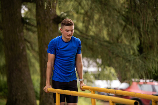 boy doing parallel bar dips outdoors. Summer sports activity.