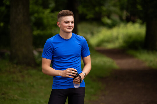 young caucasian man in a blue shirt holding a water bottle outdoors