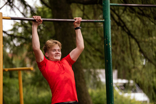 Young boy doing pull ups on horizontal bar outdoors
