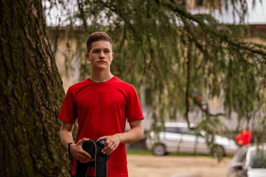 Young man in red shirt drinking from water bottle in black hip pack