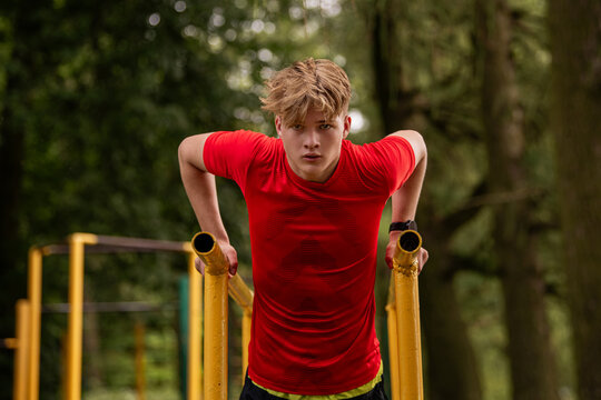 boy doing parallel bar dips outdoors. Summer sports activity.