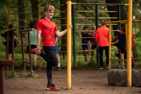 Young boy stretching on outside gym during summer workout.