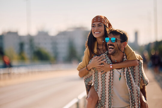 Carefree couple of festival goers piggybacking on street.