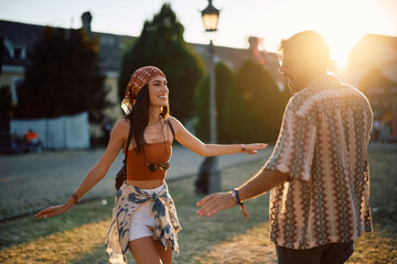 Happy festival goer dancing with her boyfriend at summer sunset.