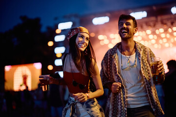 Happy couple dancing in front of stage during summer music festival at night.