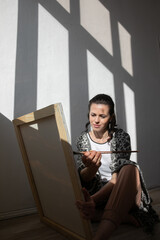 artist paints a picture on an easel with brushes and paints