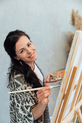 artist paints a picture on an easel with brushes and paints