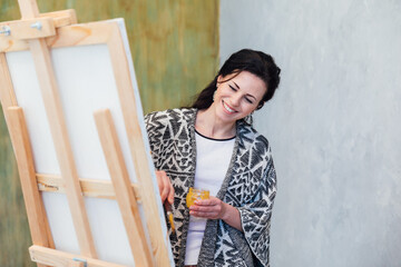 artist paints a picture on easel with brushes