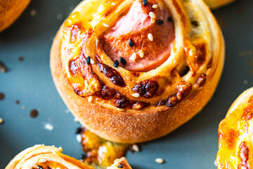 Sausage in dough, freshly baked mini rolls of puff pastry with cheese and sausage inside on a gray background.