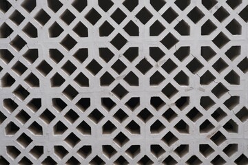 Close-up of decorative concrete ventilation blocks arranged in a geometric lattice pattern, commonly used in tropical architecture.
