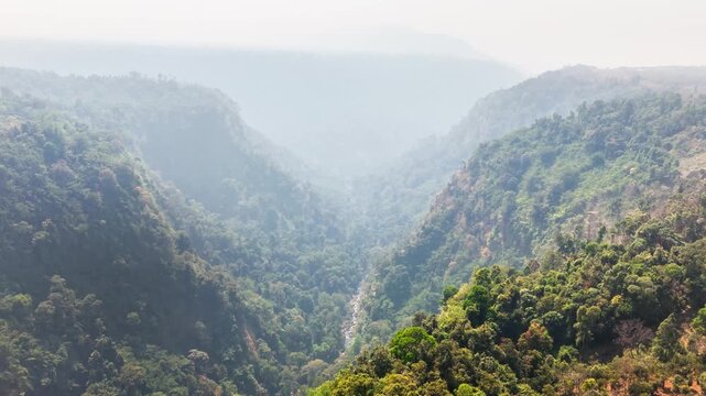 Slow drone reveal of forested canyon covered in misty atmospheric layers near Tad Fane Waterfall in the Bolaven Plateau, Pakse, Laos, capturing dense jungle and steep escarpments.