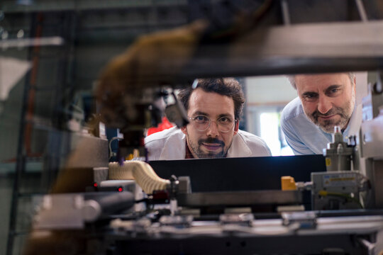 Mature businessman with colleague examining machinery at industry
