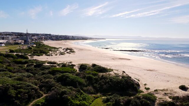 Aerial tracking shot over sandy main beach of Jeffreys Bay on Sunshine Coast