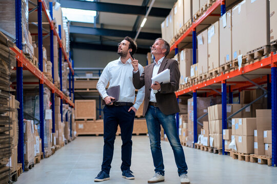 Happy senior businessman discussing over inventory with colleague at warehouse