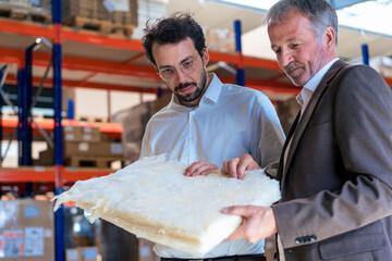 Senior businessman with colleague examining insulation at warehouse