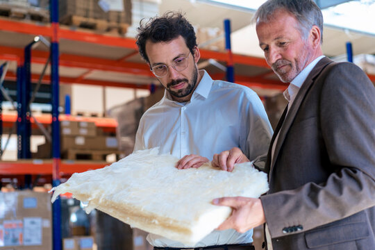 Senior businessman with colleague examining insulation at warehouse