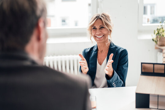 Excited real estate agent gesturing and talking to client at office