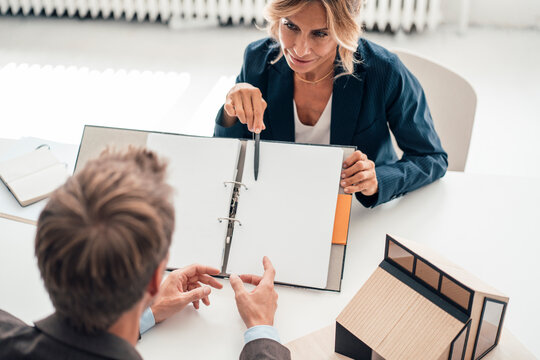 Real estate agent showing documents to customer at office