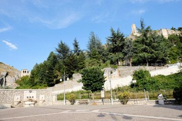 The impressive ruins of the ancient Castello di Pescina, including a prominent stone tower, stand on a rocky hill overlooking the town in Abruzzo, Italy.