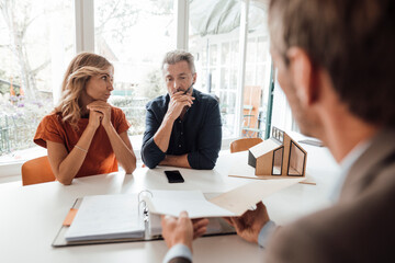 Mature couple discussing over documents with real estate agent at table