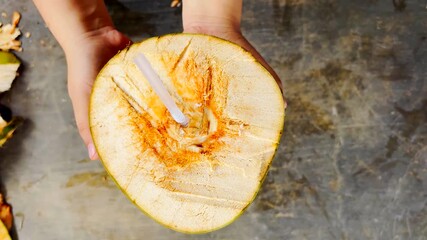 Freshly cut young green coconut and a plastic straw inserted by hand, top view, healthy and refreshing drink.