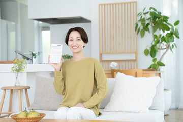 リビングで電卓を持つミドルの女性