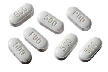 Closeup of round white pills scattered on a black background with inscriptions on surfaces