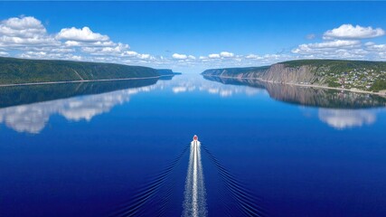 Obraz premium Scenic Aerial View of Serene Lake with Motorboat Gentle Rippling Through Calm Waters Under Clear Blue Sky
