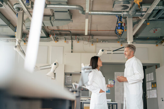 Scientists having discussion in laboratory near robotic arms