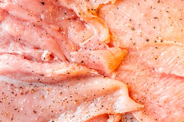 Raw chicken fillet marinated with seasonings close-up. Background with the texture of raw chicken meat. The process of making cordon bleu.