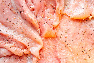 Raw chicken fillet marinated with seasonings close-up. Background with the texture of raw chicken meat. The process of making cordon bleu.