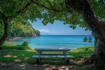 Fototapeta premium Tropical island beach view is framed by trees with a picnic table in the foreground. Perfect for travel blogs, vacation promotion, or summer-themed designs.