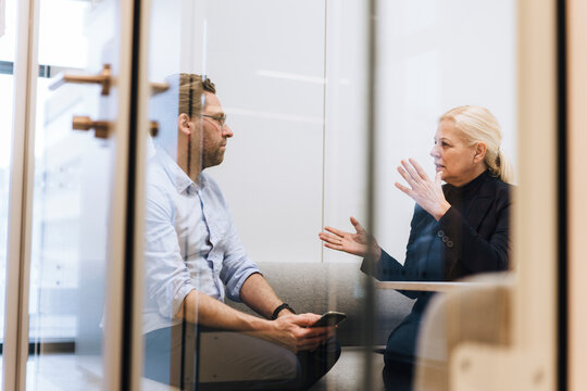Businesswoman discussing with colleague in office cubical
