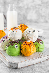 Homemade funny monster mini cakes or cake pops in a colored chocolate glaze and sugar sprinkles....