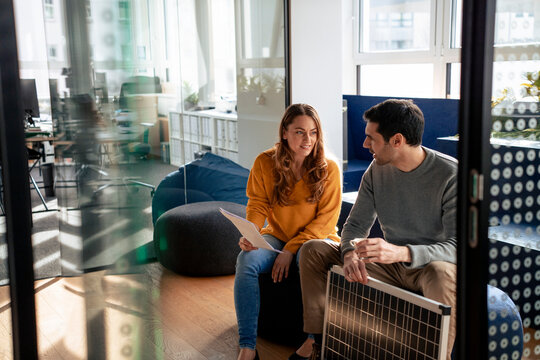 Business people discussing and sitting with solar panel in office