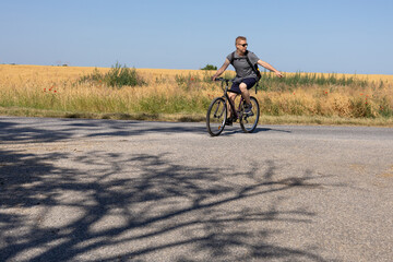 A man riding a bicycle gestures with his hand to indicate a direction while traveling along a rural...