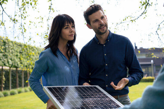 Smiling business people discussing over solar panel