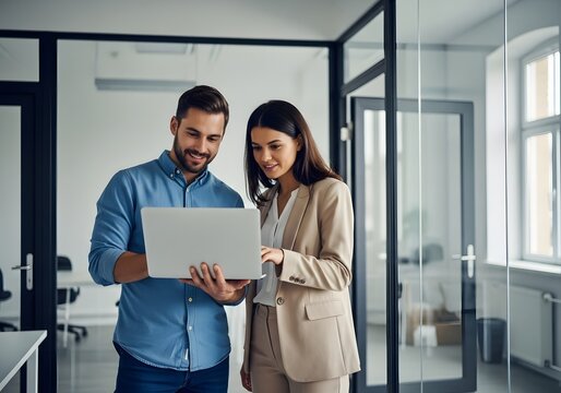 Two colleagues review a laptop in an office