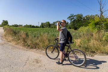 Obraz premium Cyclist drinking water on a rural summer road 