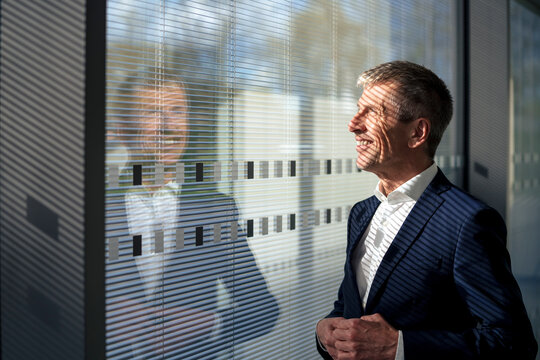 Smiling senior businessman looking out of window at office