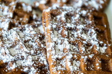 Belgian chocolate dough waffles sprinkled with powdered sugar on a white background. View from above. Close-up.