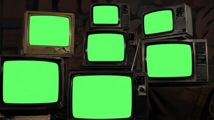 A collection of vintage television sets stacked in a dark room with bright green screens,A wall of old televisions with green screen displays stacked on top of each other - Powered by Adobe