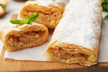 Tasty apple strudels with powdered sugar and mint on table, closeup