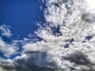 A vibrant blue sky partially obscured by a mix of bright white and darker grey clouds