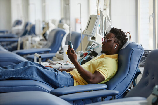 Man donating blood and using smart phone