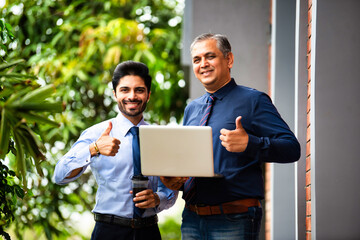 Asian corporate professionals with laptop walking brainstorming outside contemporary office