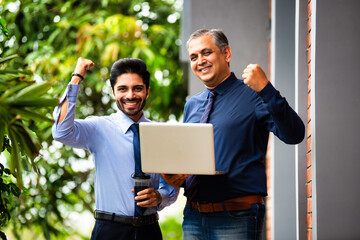 Asian corporate professionals with laptop walking brainstorming outside contemporary office