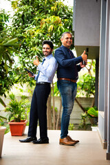 Indian corporate professionals walk with tablet, engaged in discussion outside office building